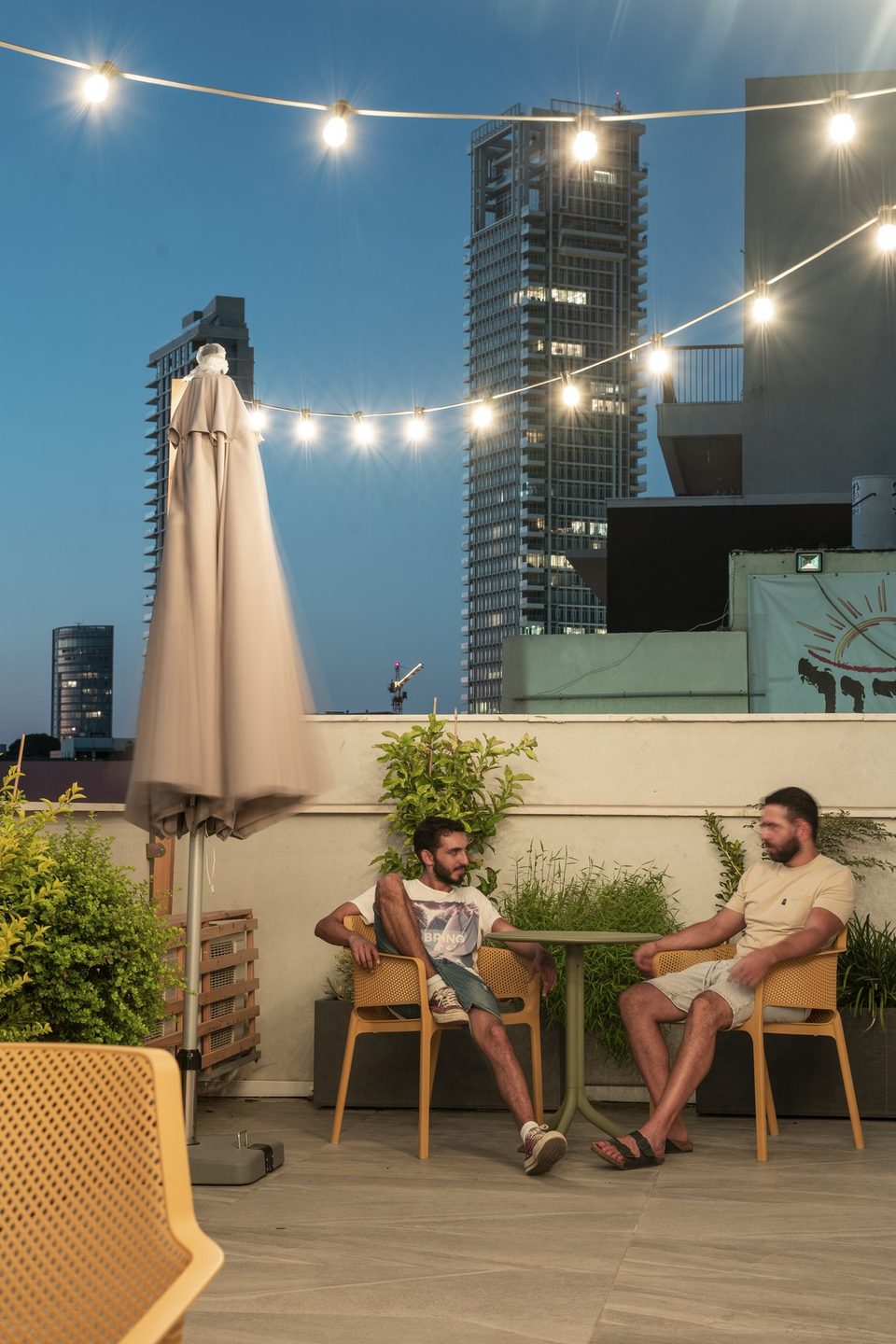 Two guests on the rooftop under the lights in the evening