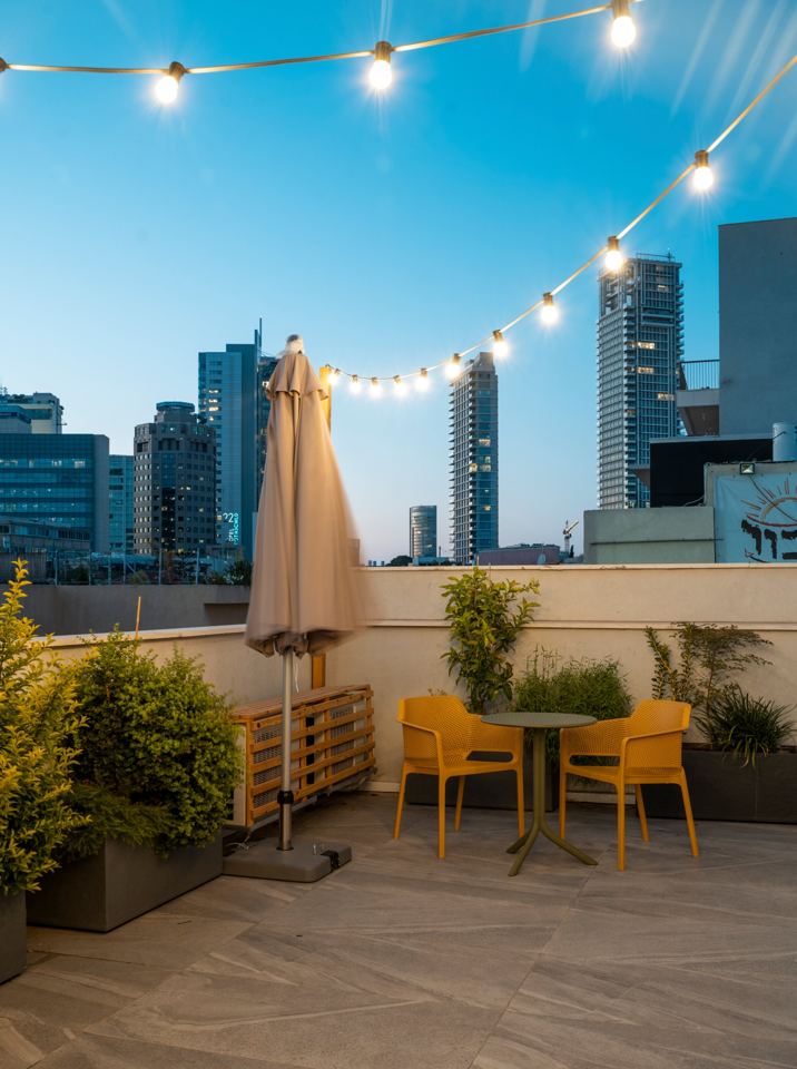 Terrasse sur le toit avec guirlandes, chaises jaunes et vue sur les tours