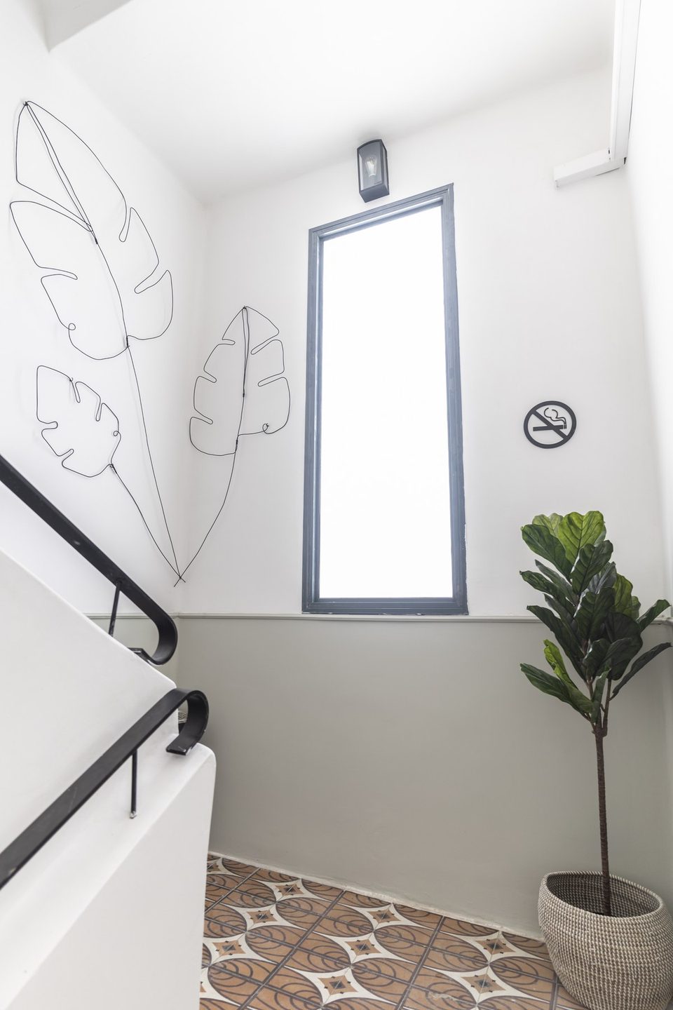 A bright stairwell with line art and a potted plant