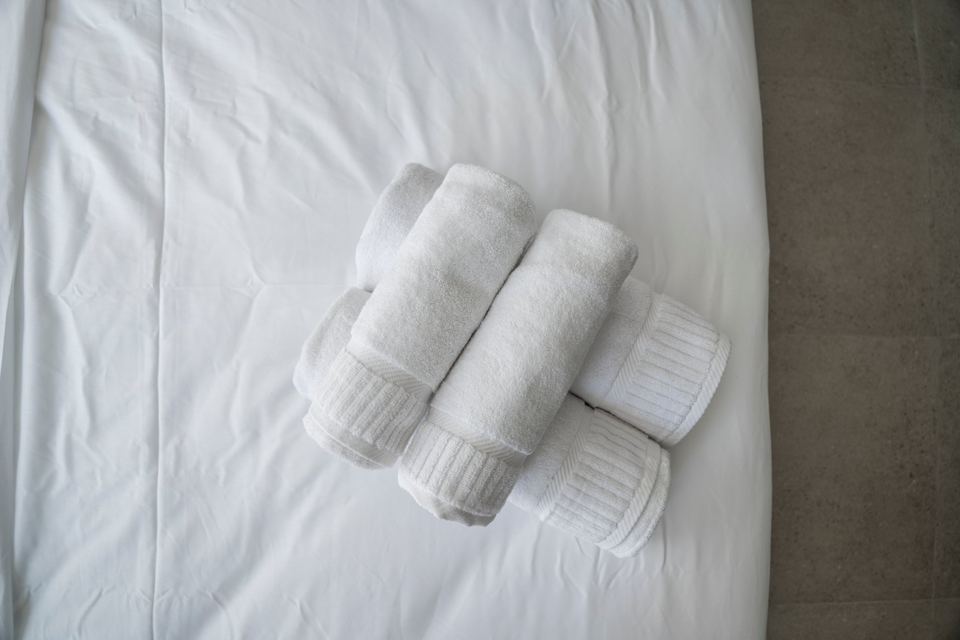 Rolled white towels on a made bed